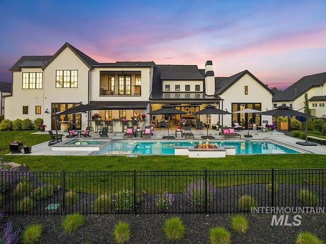 back of property at dusk with a fenced in pool, a yard, a standing seam roof, a patio area, and fence private yard