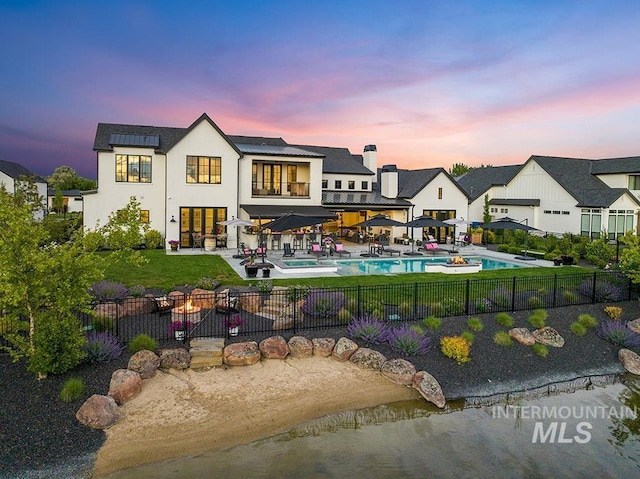 rear view of house featuring a fenced in pool, a patio, stucco siding, roof mounted solar panels, and a fenced backyard