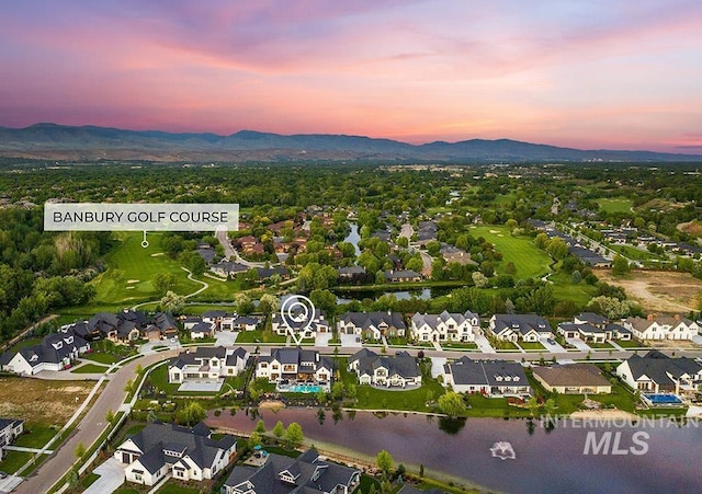 aerial view at dusk featuring a residential view and a water and mountain view