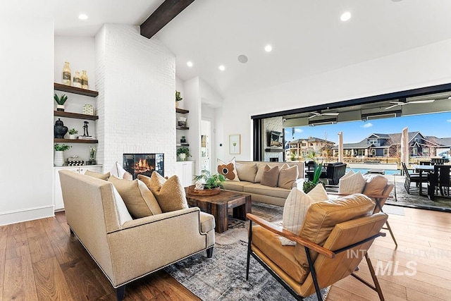 living area featuring hardwood / wood-style flooring, a brick fireplace, beam ceiling, and recessed lighting