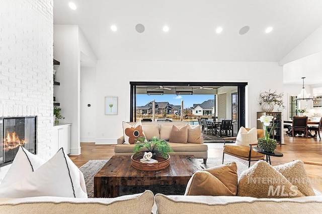 living room featuring baseboards, wood finished floors, a fireplace, high vaulted ceiling, and recessed lighting