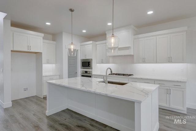 kitchen featuring white cabinetry, a kitchen island with sink, hanging light fixtures, and appliances with stainless steel finishes