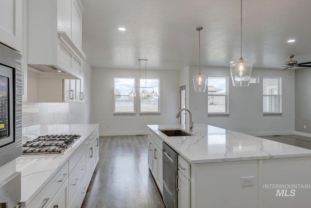 kitchen with hanging light fixtures, plenty of natural light, a kitchen island with sink, and sink