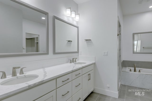 bathroom with tiled bath, tile patterned flooring, and vanity