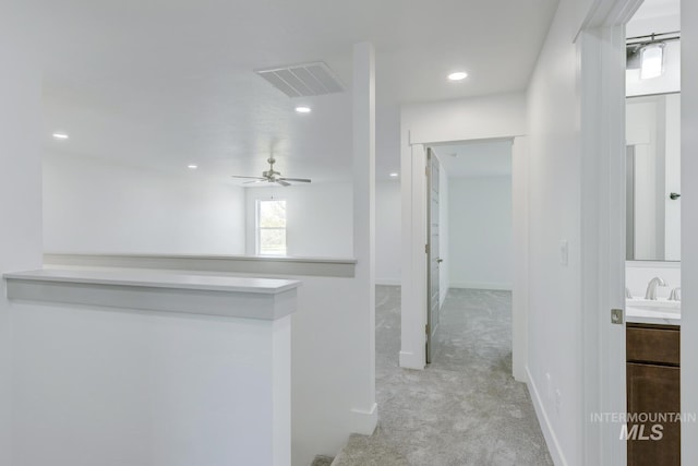 hallway featuring sink and light carpet