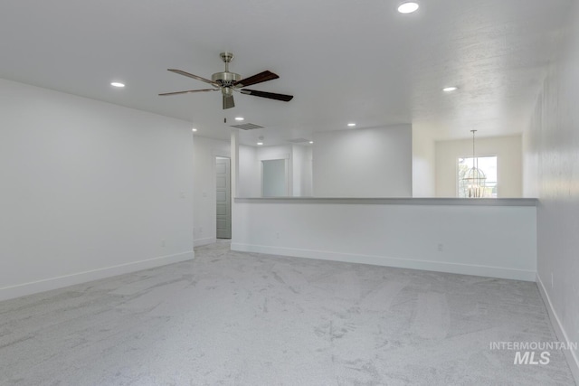 spare room featuring ceiling fan with notable chandelier and light colored carpet