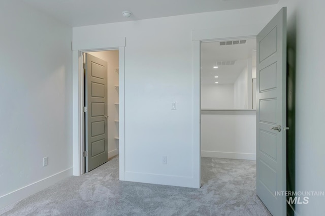 unfurnished bedroom featuring light carpet and a closet