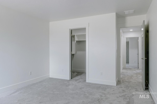 unfurnished bedroom featuring light colored carpet, a spacious closet, and a closet