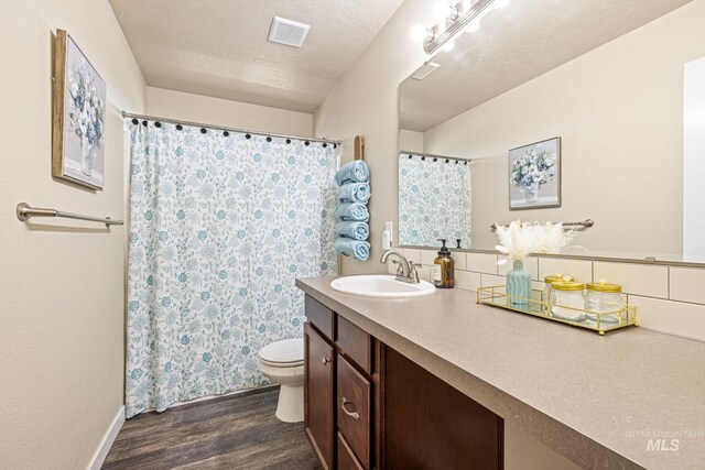 16848 Loggia Ave, Caldwell, ID 83607 - bathroom featuring wood finished floors, toilet, vanity, baseboards, and curtained shower