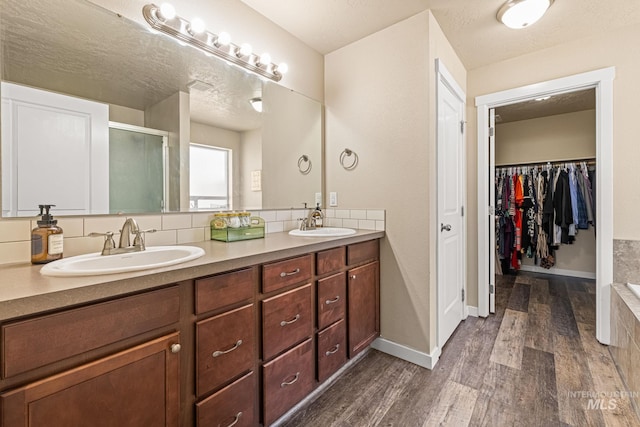 16848 Loggia Ave, Caldwell, ID 83607 - bathroom with wood finished floors, double vanity, a shower stall, and a spacious closet