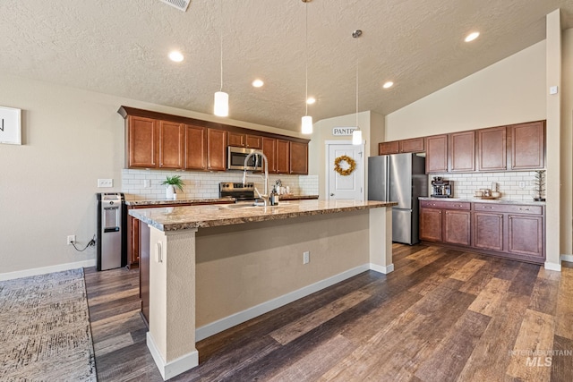 16848 Loggia Ave, Caldwell, ID 83607 - kitchen with appliances with stainless steel finishes, a kitchen island with sink, dark wood-style flooring, backsplash, and a textured ceiling