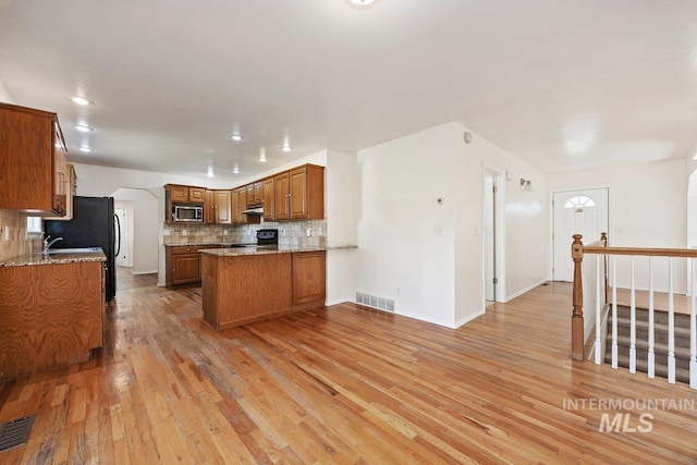 646 W Falls Ave, Twin Falls, ID 83301 - kitchen featuring stainless steel microwave, range, light wood finished floors, brown cabinets, and tasteful backsplash