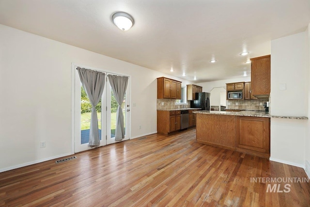 646 W Falls Ave, Twin Falls, ID 83301 - kitchen featuring stainless steel appliances, backsplash, light wood-type flooring, a peninsula, and brown cabinets