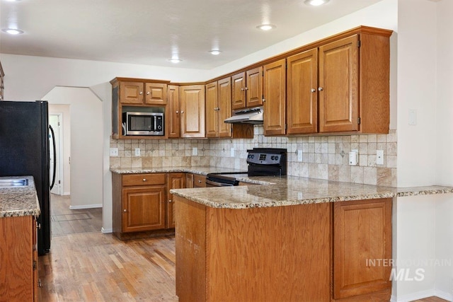 646 W Falls Ave, Twin Falls, ID 83301 - kitchen with black appliances, under cabinet range hood, a peninsula, brown cabinets, and light wood finished floors