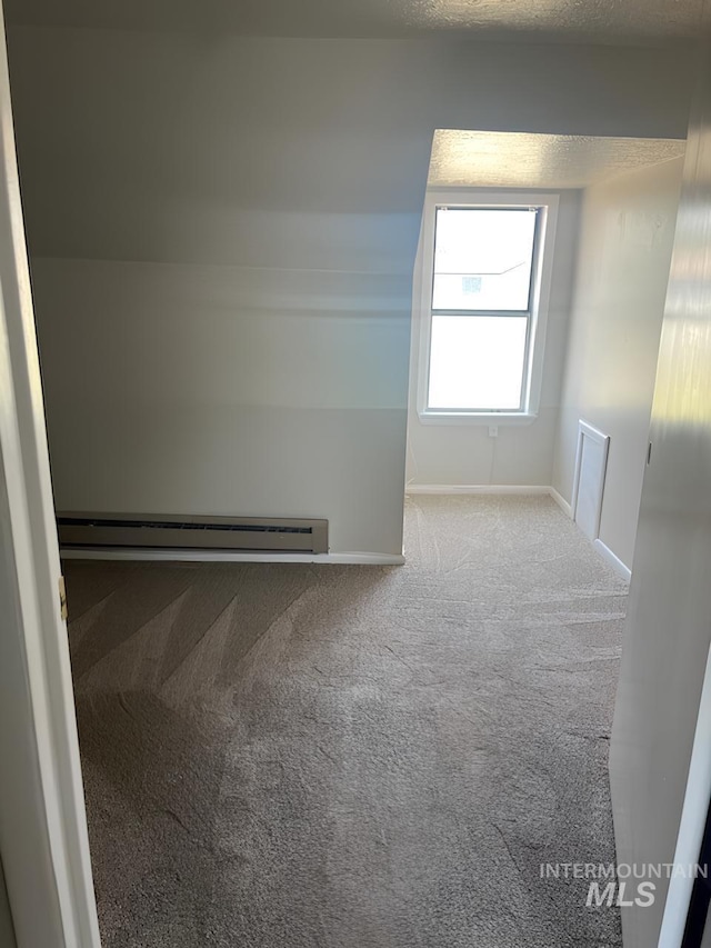 carpeted spare room featuring baseboard heating and a textured ceiling