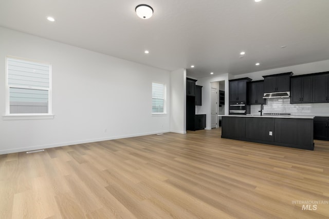 2386 N Leatherwood Ave, Star, ID 83669 - kitchen featuring open floor plan, dark cabinets, light countertops, tasteful backsplash, and recessed lighting