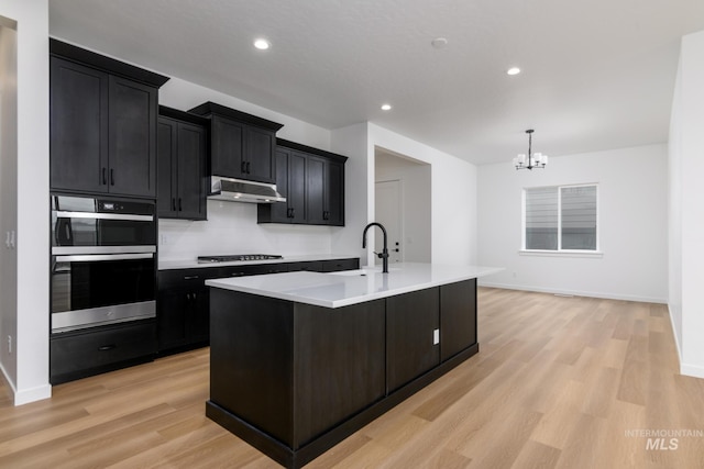 2386 N Leatherwood Ave, Star, ID 83669 - kitchen featuring under cabinet range hood, a sink, dark cabinets, a chandelier, and recessed lighting