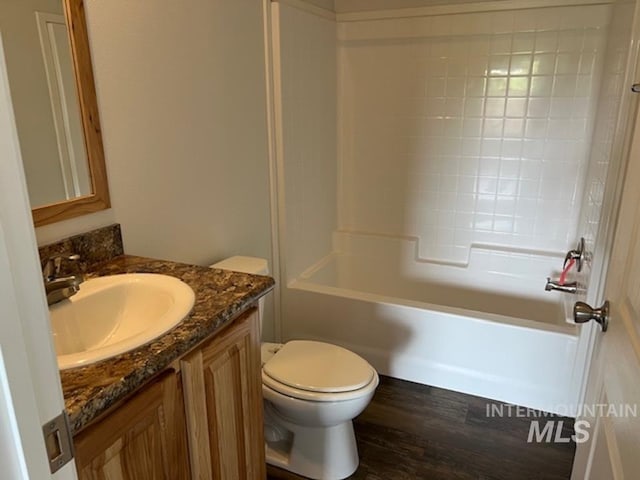 bathroom featuring vanity, wood finished floors, toilet, and washtub / shower combination