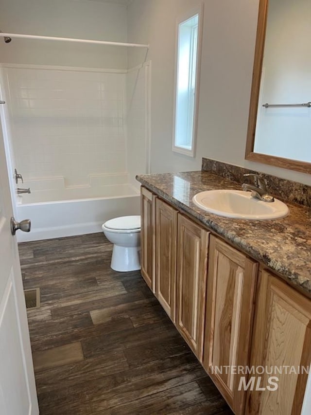 full bathroom with toilet, wood finished floors, vanity, and washtub / shower combination