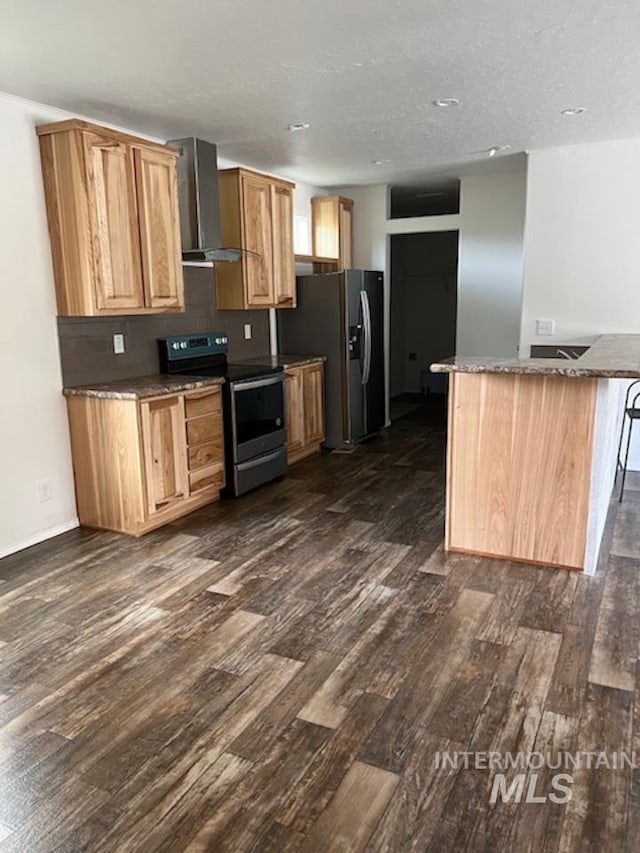 kitchen featuring stainless steel appliances, wall chimney range hood, dark wood finished floors, baseboards, and a center island