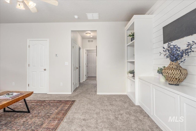 hallway featuring light carpet and a textured ceiling