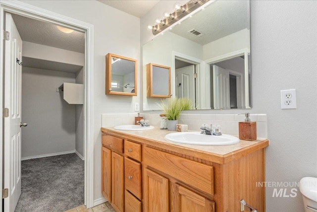 bathroom with tasteful backsplash, vanity, and a textured ceiling