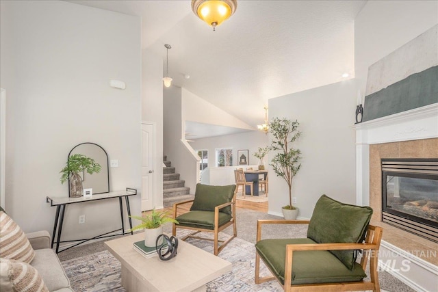 living room featuring high vaulted ceiling and a tile fireplace