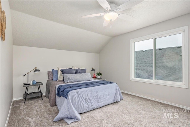 carpeted bedroom featuring ceiling fan, vaulted ceiling, and a textured ceiling