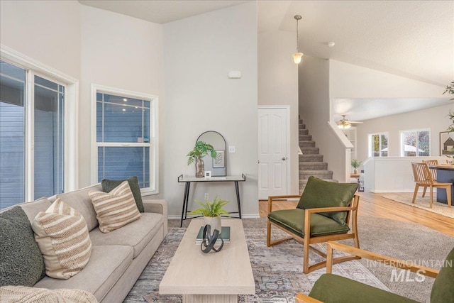 living room featuring high vaulted ceiling, ceiling fan, and light wood-type flooring