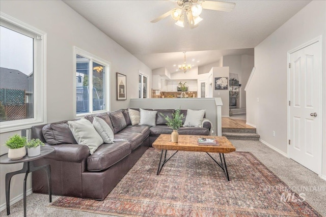 living room with lofted ceiling, ceiling fan with notable chandelier, and light carpet