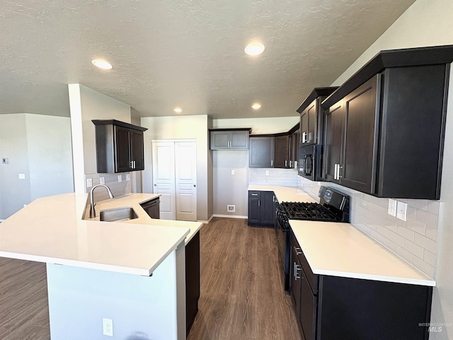 1786 E Cave Falls St, Kuna, ID 83634 - kitchen featuring a sink, black appliances, a peninsula, dark wood-type flooring, and backsplash