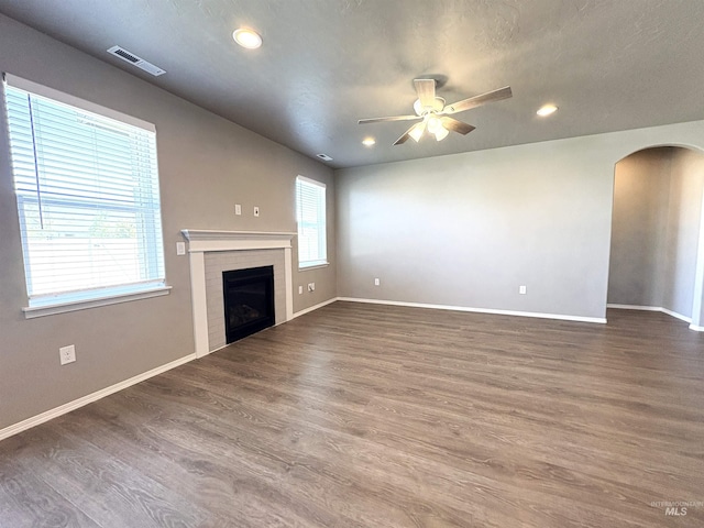 1786 E Cave Falls St, Kuna, ID 83634 - unfurnished living room with arched walkways, ceiling fan, a tiled fireplace, baseboards, and recessed lighting