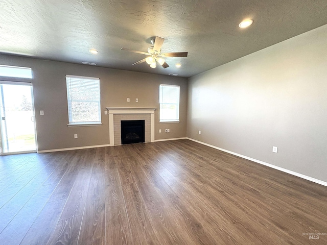 1786 E Cave Falls St, Kuna, ID 83634 - unfurnished living room with a ceiling fan, baseboards, dark wood-style flooring, a textured ceiling, and a fireplace
