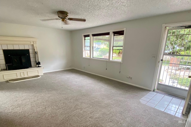 unfurnished living room featuring carpet flooring, ceiling fan, a textured ceiling, and a tile fireplace