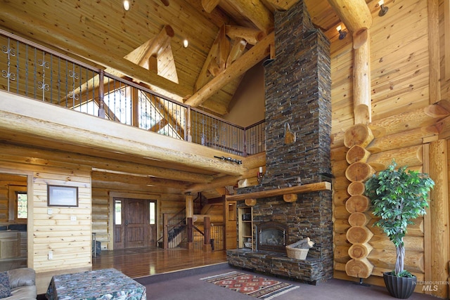 unfurnished living room with a stone fireplace, log walls, high vaulted ceiling, and beamed ceiling