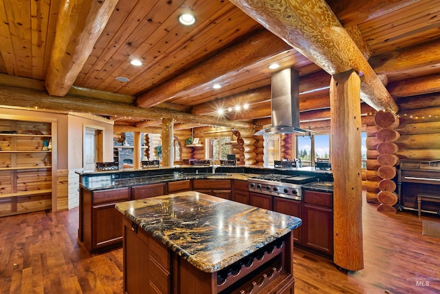 kitchen with a center island, island range hood, beam ceiling, and rustic walls