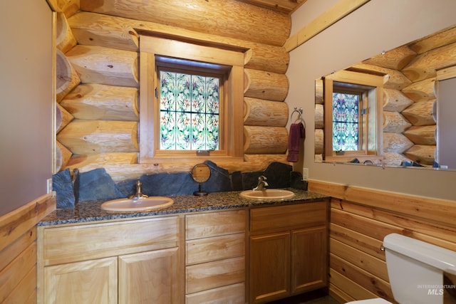 bathroom with vanity, toilet, and rustic walls