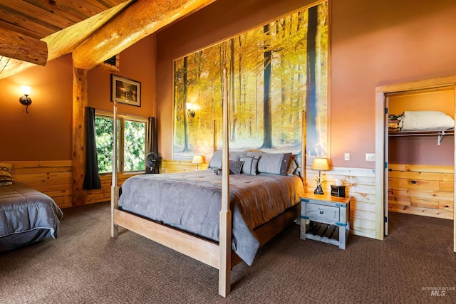 bedroom featuring beam ceiling, wood ceiling, wooden walls, and dark carpet