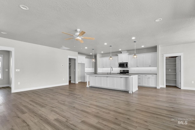 kitchen featuring an island with sink, sink, white cabinetry, ceiling fan, and light wood-type flooring