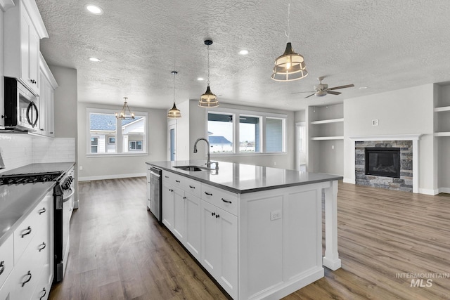 kitchen featuring white cabinetry, a healthy amount of sunlight, a center island with sink, and sink