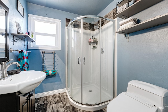bathroom featuring vanity, baseboards, a stall shower, and toilet