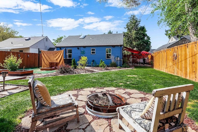 rear view of property featuring a fenced backyard, a yard, and an outdoor fire pit