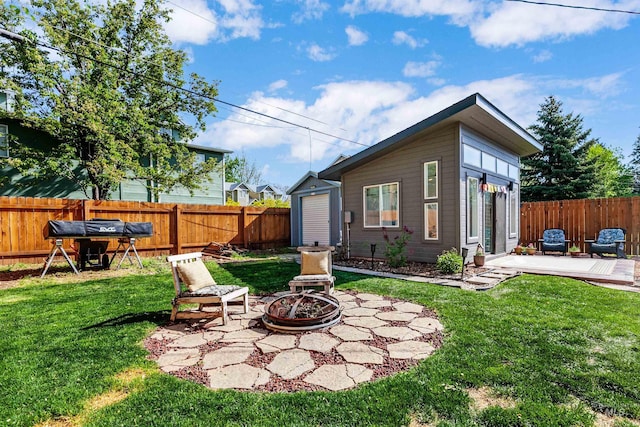 rear view of property featuring a fenced backyard, a yard, an outdoor fire pit, and a patio area