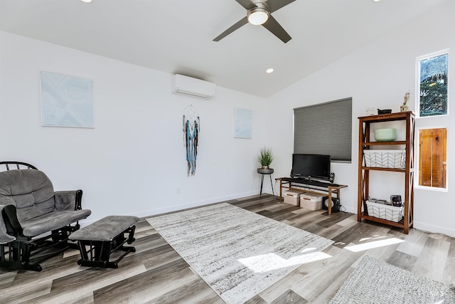 living area with ceiling fan, an AC wall unit, baseboards, wood finished floors, and vaulted ceiling