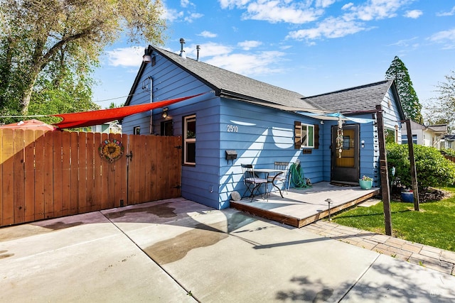 back of property with a shingled roof, fence, and a deck