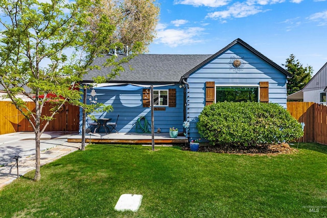 bungalow-style home featuring fence, a wooden deck, a shingled roof, and a front lawn