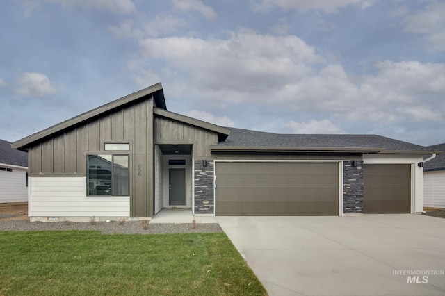 view of front of home featuring roof with shingles, board and batten siding, a front yard, a garage, and driveway