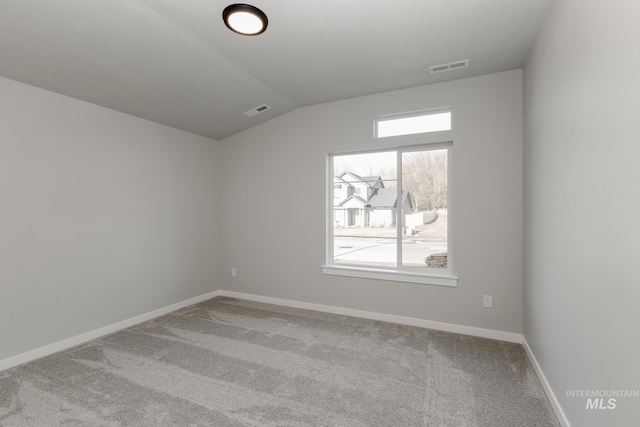 carpeted empty room featuring vaulted ceiling