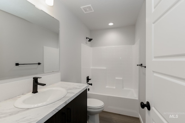 bathroom featuring visible vents, toilet, wood finished floors, vanity, and washtub / shower combination