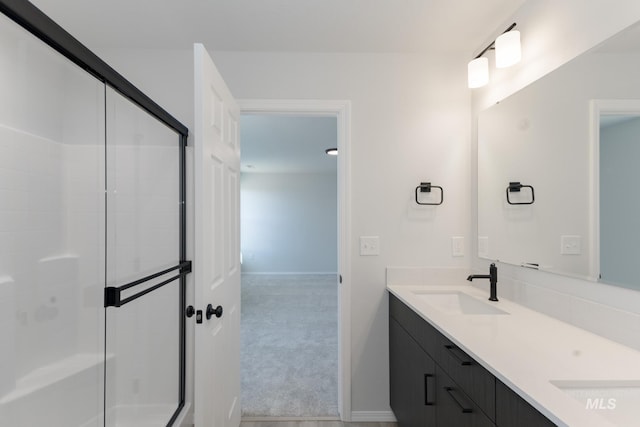 full bath featuring double vanity, baseboards, an enclosed shower, and a sink